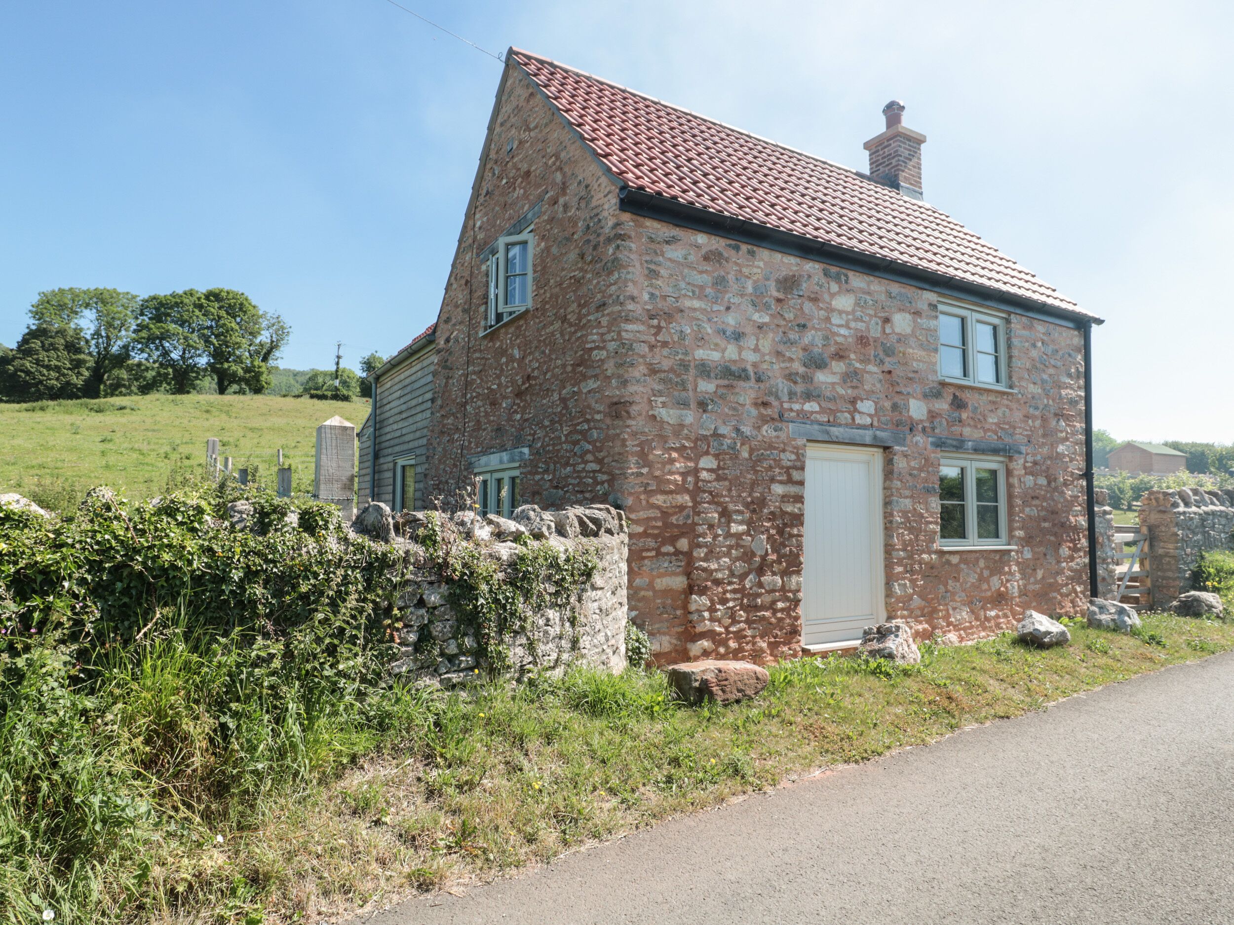 A stone house with a red-tiled roof, a white door, and a small window.