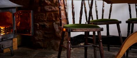 A rustic interior with wooden chairs and a stone wall.