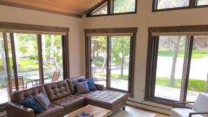 A spacious living room with a sectional sofa, a wooden coffee table, and large windows offering a view of a landscaped garden. - Pet-friendly 5 bed/4 bath home, just minutes to Beaver Creek, Avon, and Vail (Avon)
