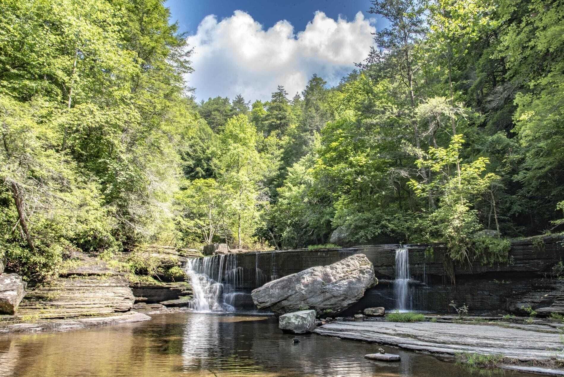 Paisagem natural com cachoeira, lago e floresta densa.