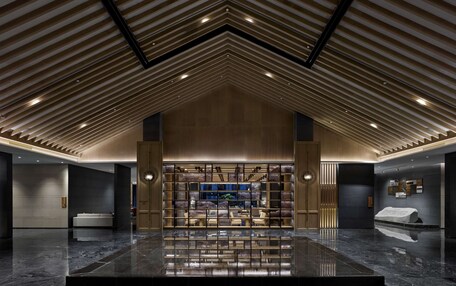 A spacious lobby with a high ceiling, a central seating area, and a reflective marble floor.