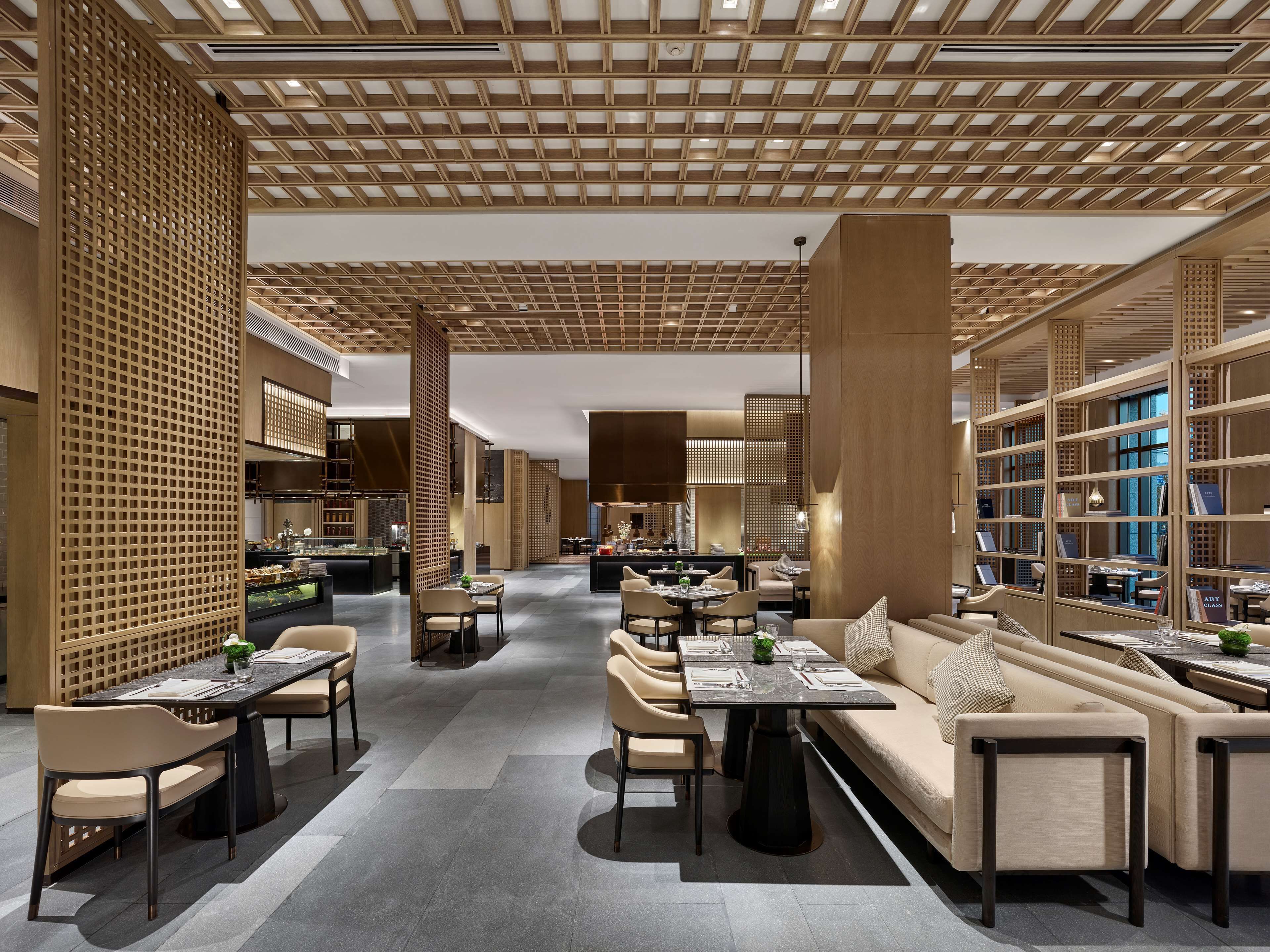 A modern interior with a central dining area, seating arrangements, and a library.
