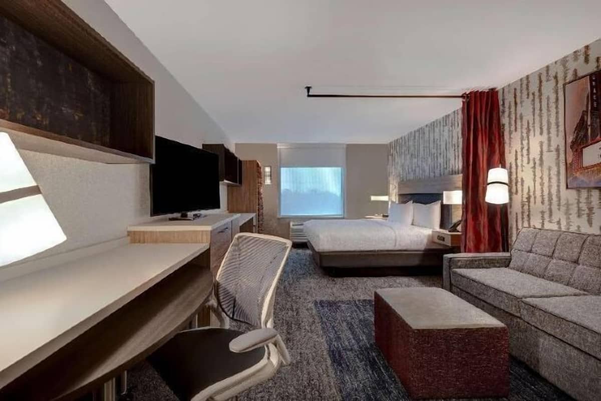 Une chambre d’hôtel comprenant un lit, un bureau, une chaise, un canapé et un téléviseur.