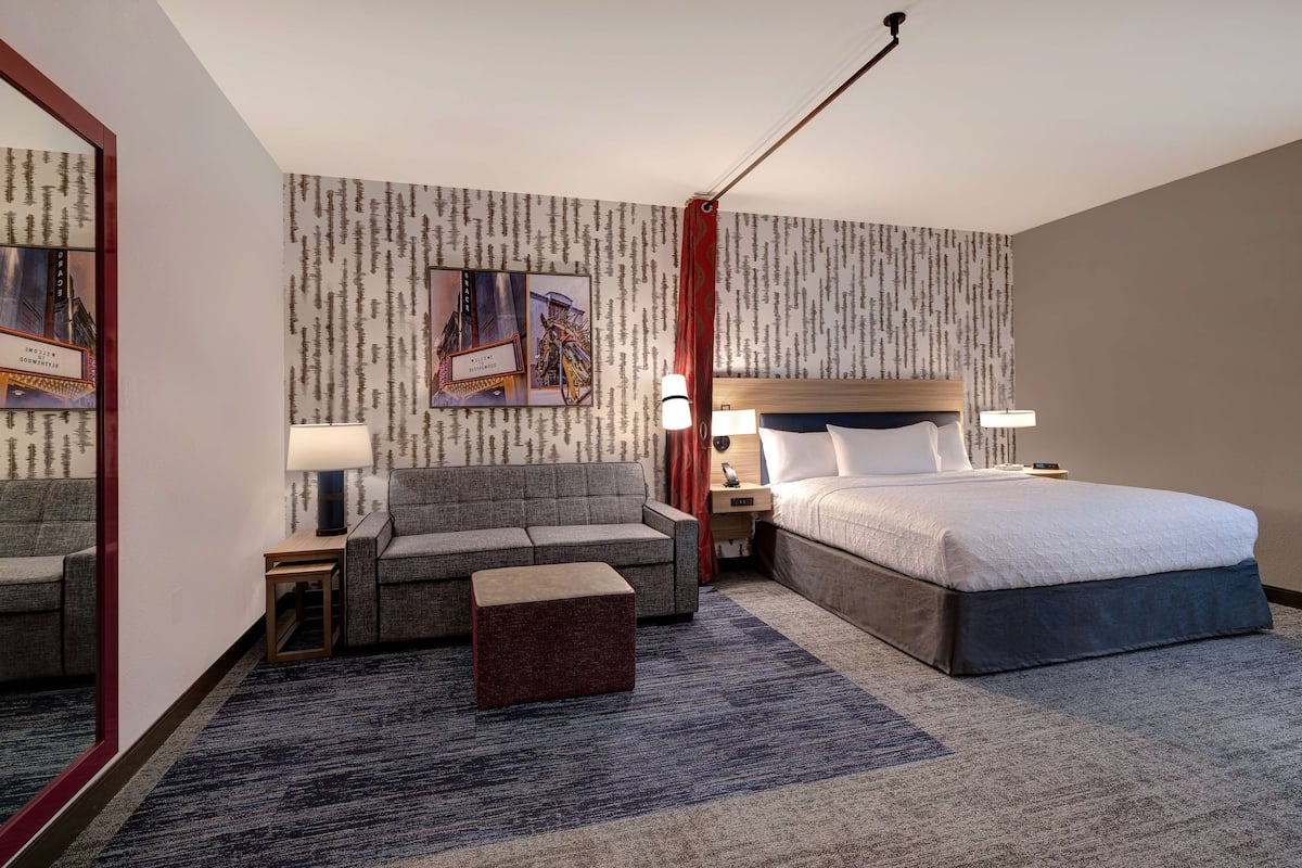 Une chambre d’hôtel avec un grand lit, un canapé, une petite table et une table de chevet.