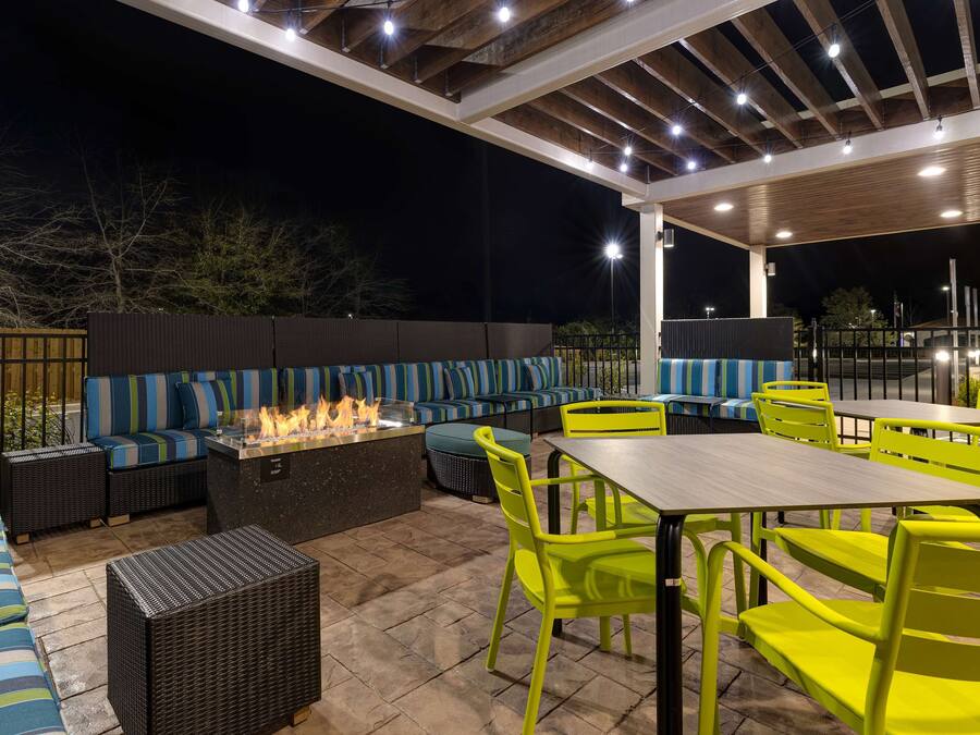 Un espacio al aire libre con patio, asientos, una chimenea y sillas de color amarillo brillante.
