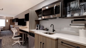 A modern kitchen with a built-in microwave, stainless steel appliances, a coffee maker, and a dish rack.