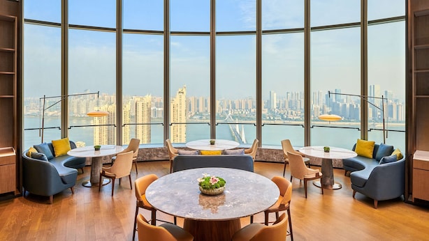 A modern lounge with large windows, round tables, and comfortable seating. - Hilton Changsha Riverside (Changsha)