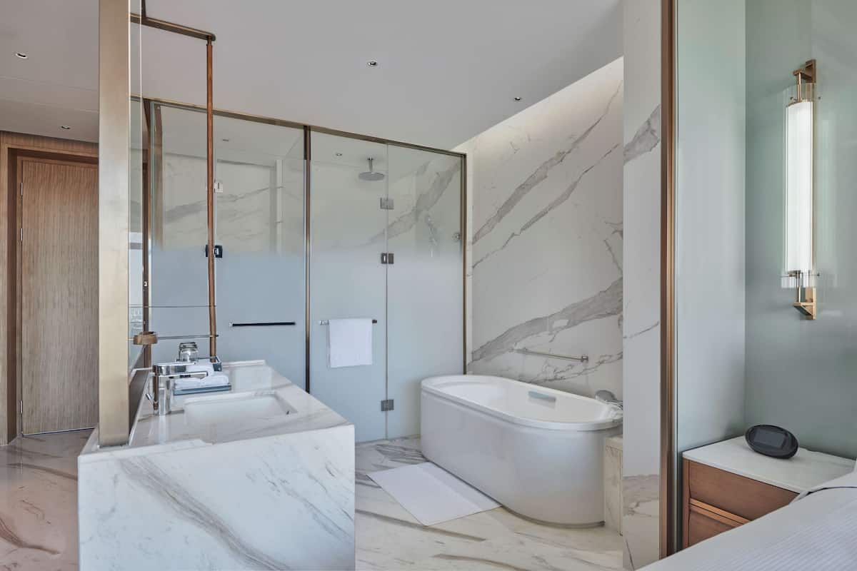 A modern bathroom with a glass-enclosed shower, a freestanding bathtub, and a marble vanity.