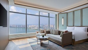 A modern hotel room with a large window offering a city view, a sofa, a bed, and a small table. - Hilton Changsha Riverside (Changsha)