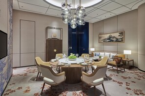 A modern dining room with a round table, chairs, a chandelier, and a painting on the wall. - Hilton Changsha Riverside (Changsha)