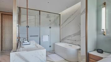 A modern bathroom with a glass-enclosed shower, a marble sink, and a freestanding bathtub.