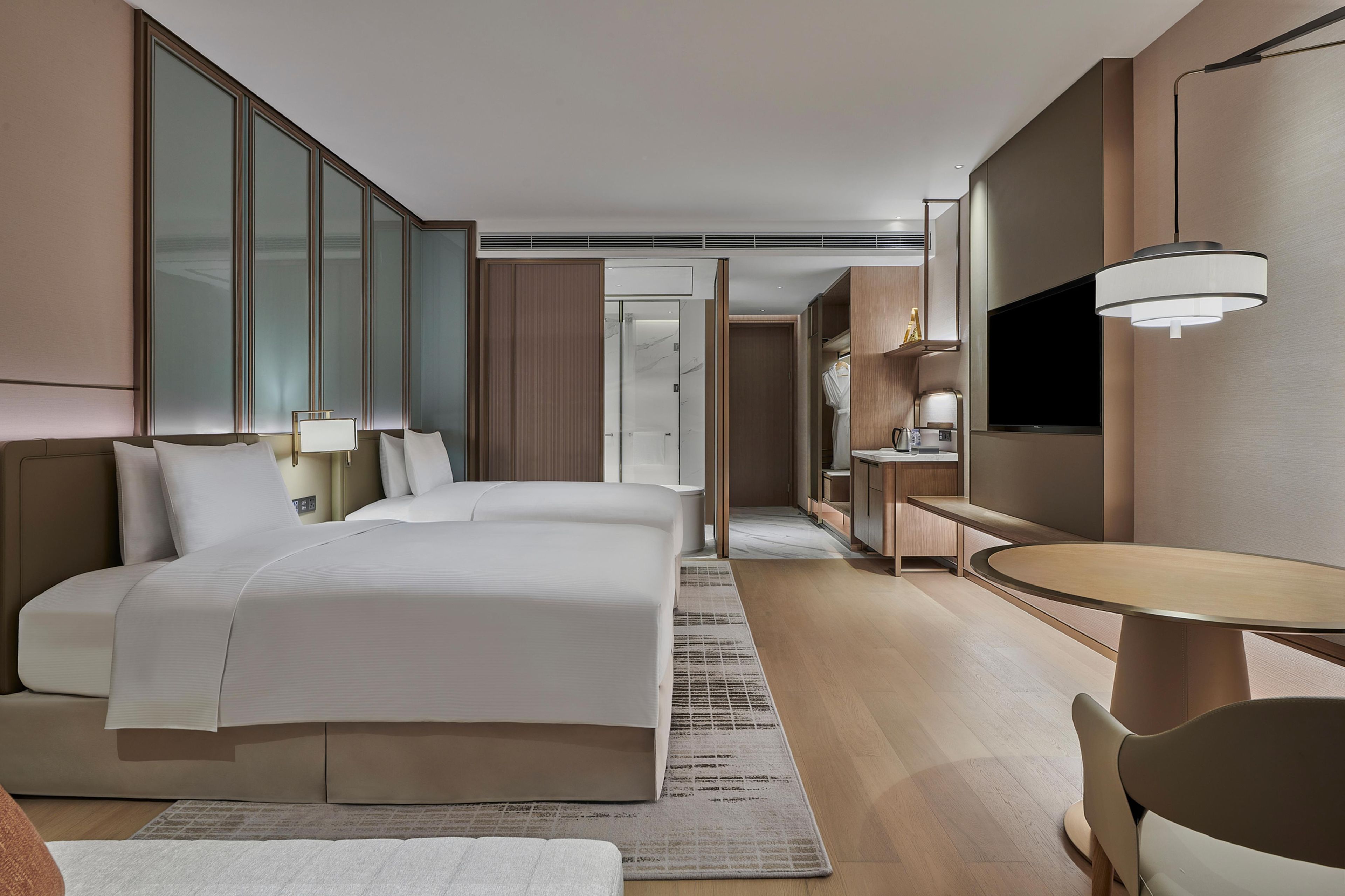 A hotel room with a large bed, a desk, a chair, a television, and a wardrobe.