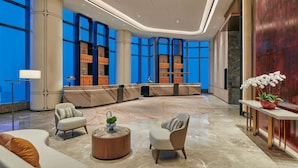 A modern lobby with a curved reception desk, seating area, and large windows. - Hilton Changsha Riverside (Changsha)