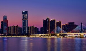 A city skyline with modern high-rise buildings and a prominent bridge with illuminated cables. - Hilton Changsha Riverside (Changsha)