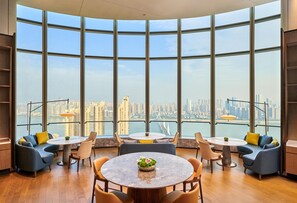 A modern interior with large windows, a round table, and seating arrangements.