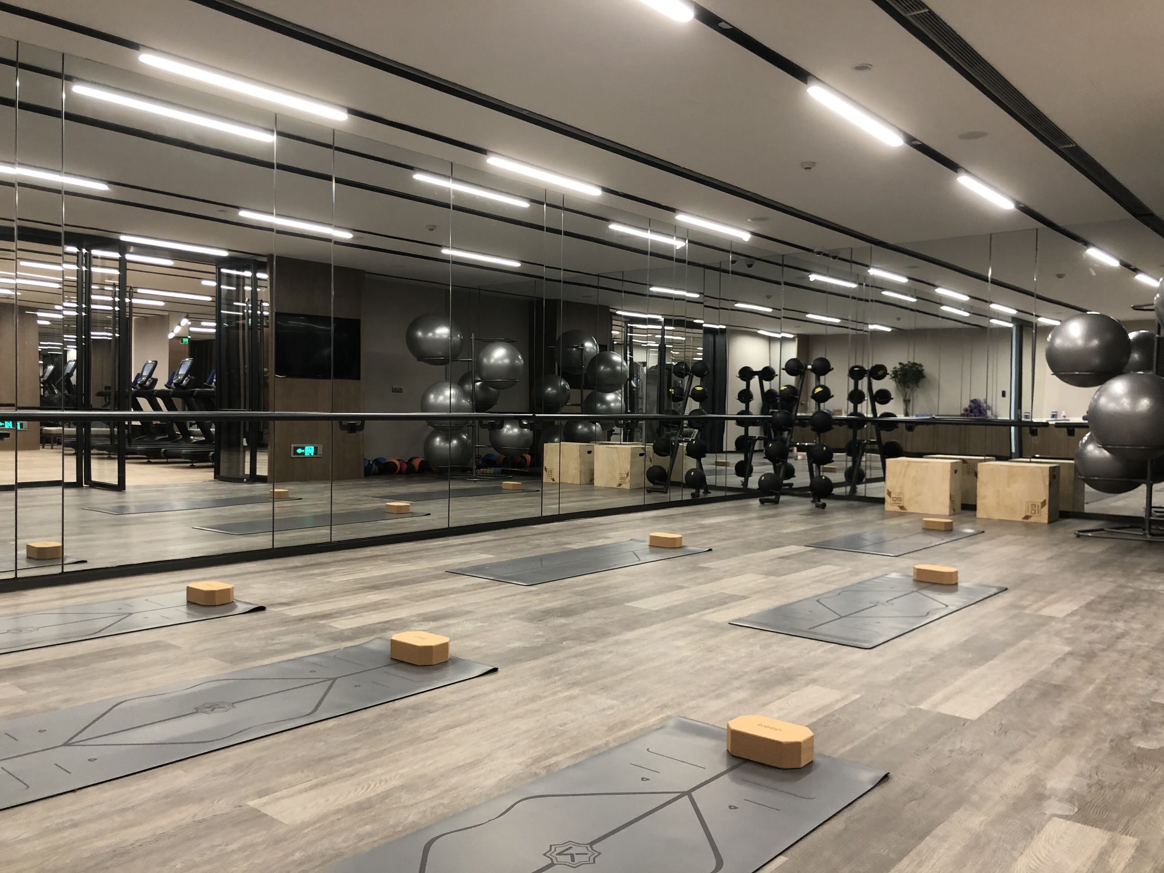 Ein Fitnessraum mit Trainingsgeräten, Holzboden und Spiegeln.