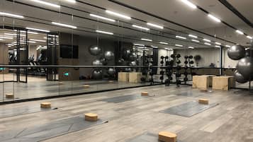 Ein Fitnessraum mit Trainingsgeräten, Holzboden und Spiegeln.