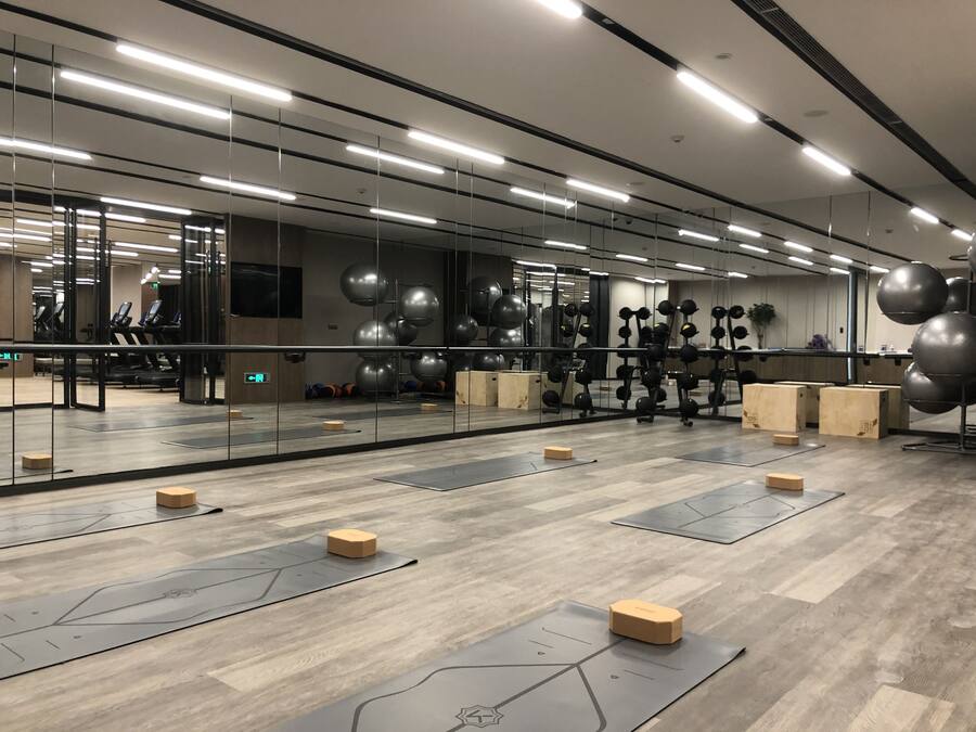 A gym with exercise equipment, wooden flooring, and mirrors.