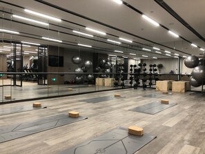 Kuntosali, jossa on kuntoiluvälineitä, puulattia ja peilit.