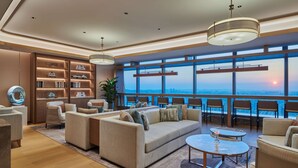 A modern living room with a sofa, armchairs, a coffee table, and a large window offering a city view. - Hilton Changsha Riverside (Changsha)