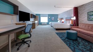 Une chambre d’hôtel équipée d’un bureau, d’une chaise, d’une télévision, d’un lit et d’un canapé.