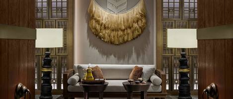 A room with a sofa, two side tables, and decorative lamps.