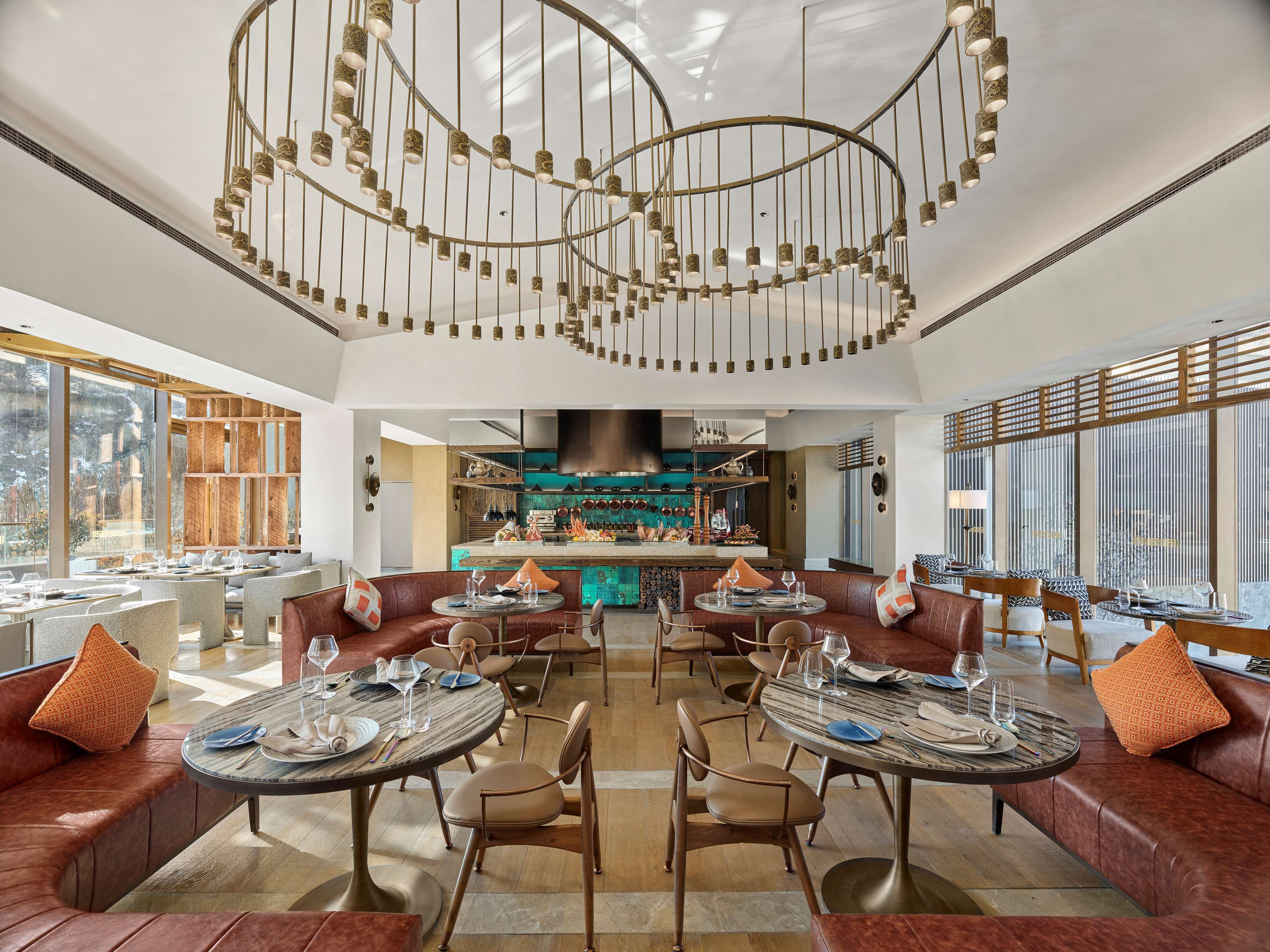 Un espace repas moderne avec des canapés en cuir, des tables rondes et une cuisine centrale.
