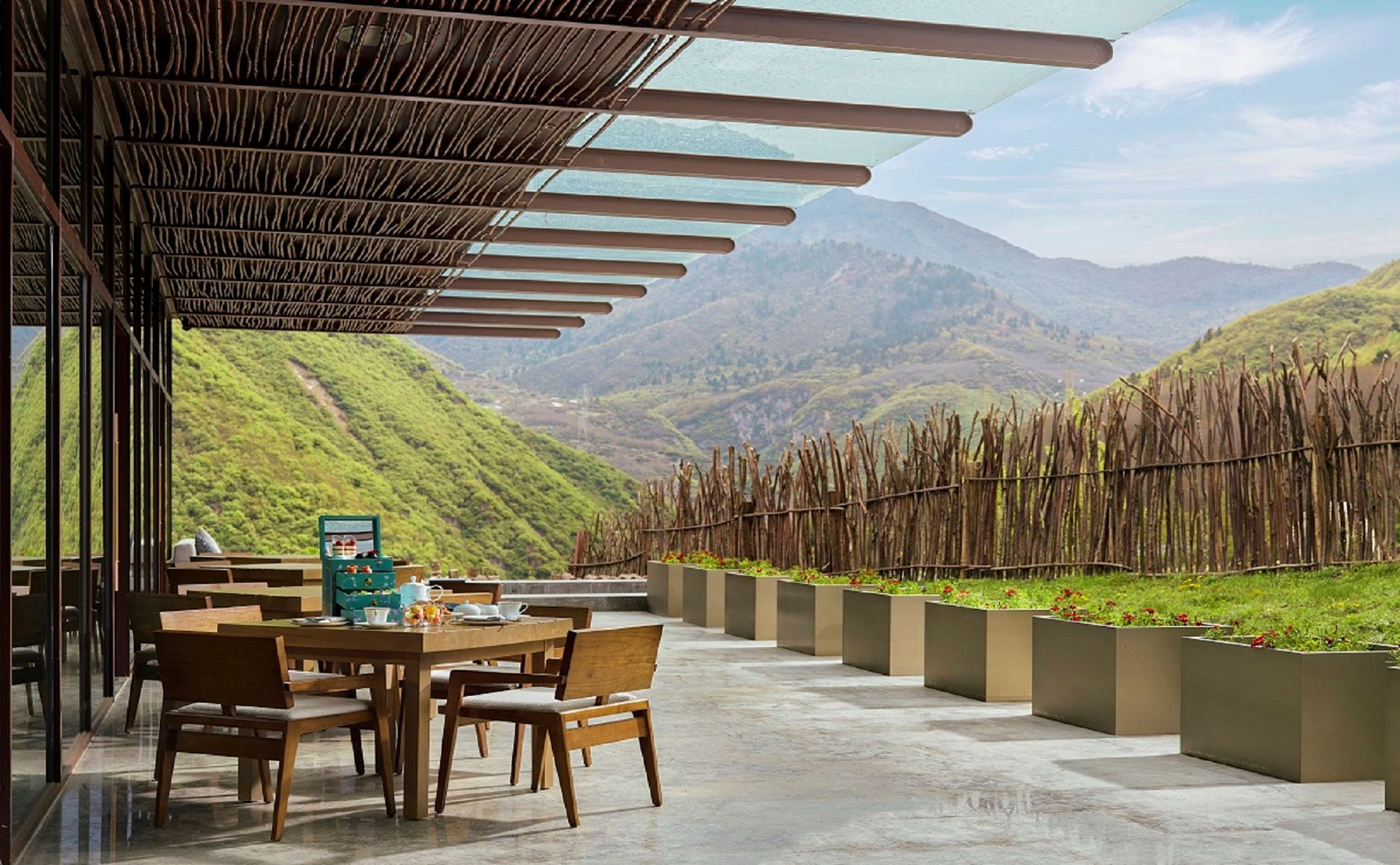 Un coin repas avec une table dressée pour deux personnes, offrant une vue sur un paysage montagneux.