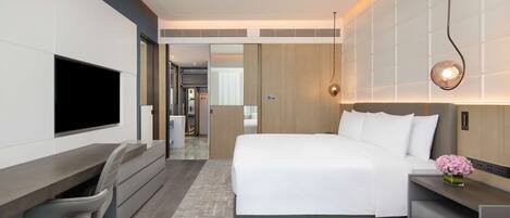 Una habitación de hotel moderna con una cama, un escritorio, una silla, un televisor y una pequeña mesa con un florero.