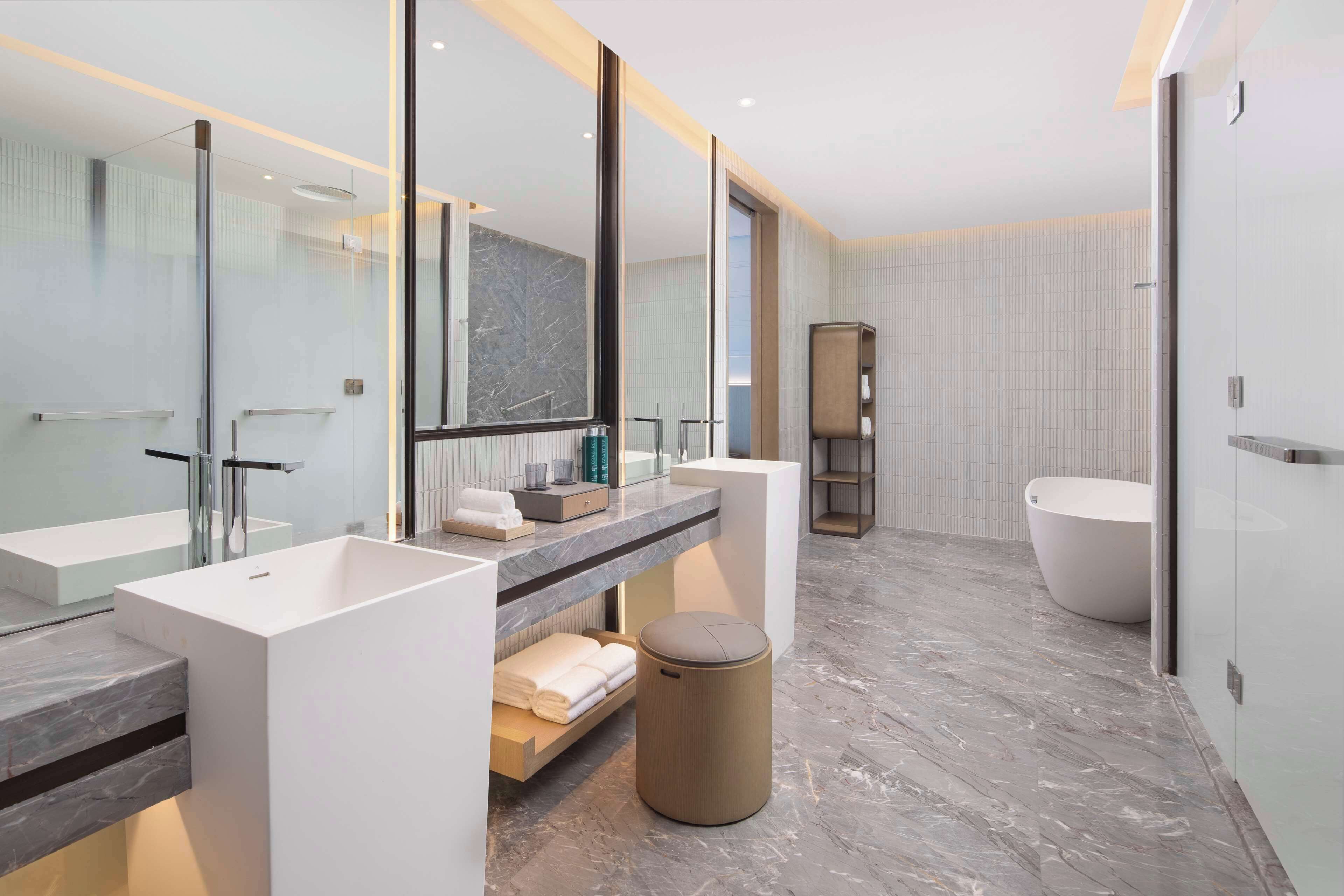Un baño moderno con dos lavamanos, un espejo grande, una bañera y un mueble de tocador con toallas.
