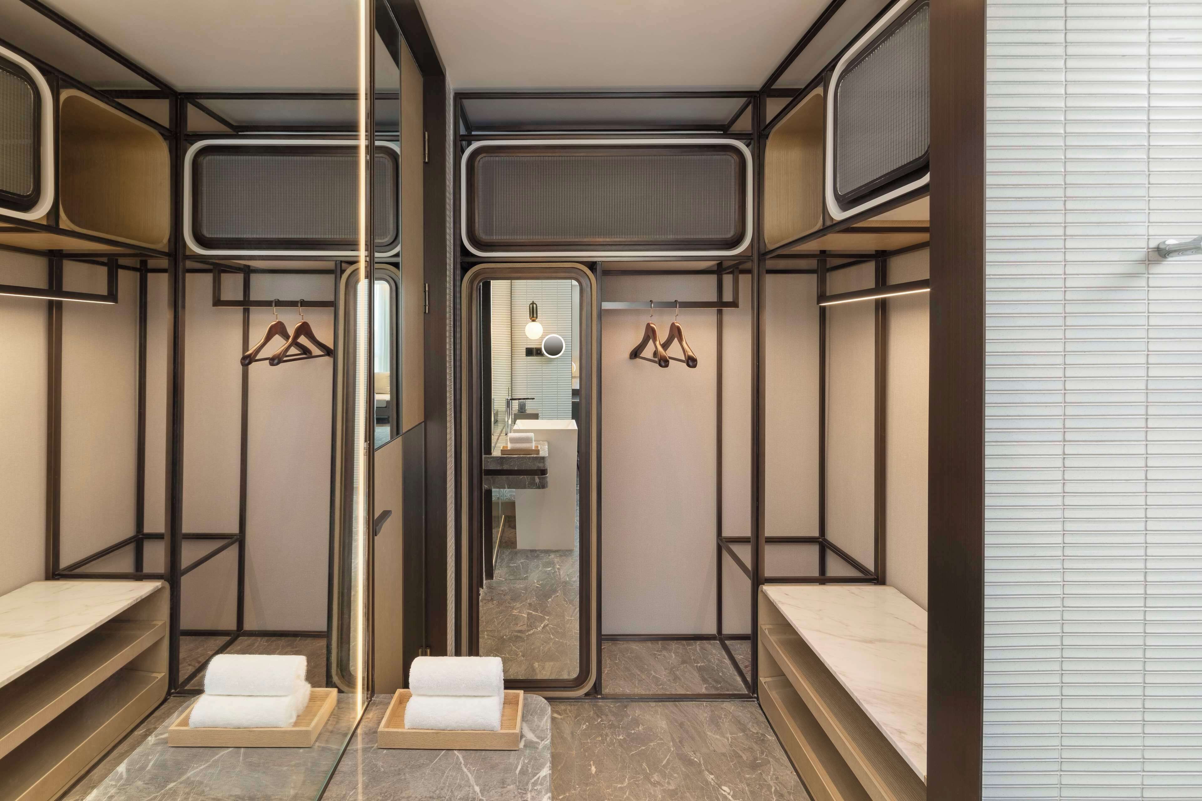 A modern bathroom with mirrored walls, wooden shelves, and marble flooring.