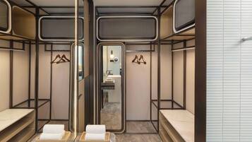 Un baño moderno con paredes espejadas, estantes de madera y suelo de mármol.