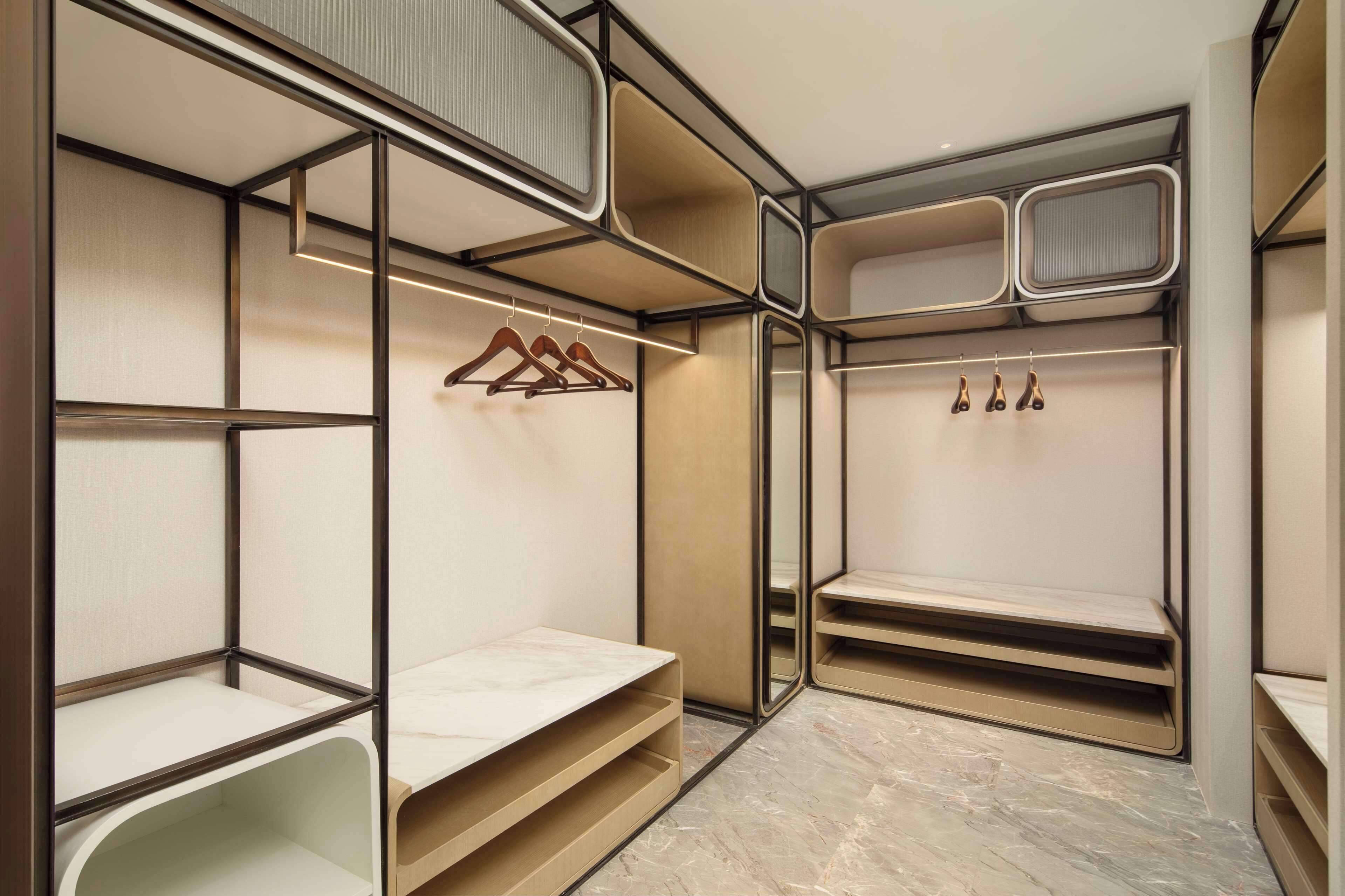 Un dressing accessible sans porte, doté d’étagères ouvertes, d’une tringle et d’une porte miroir.