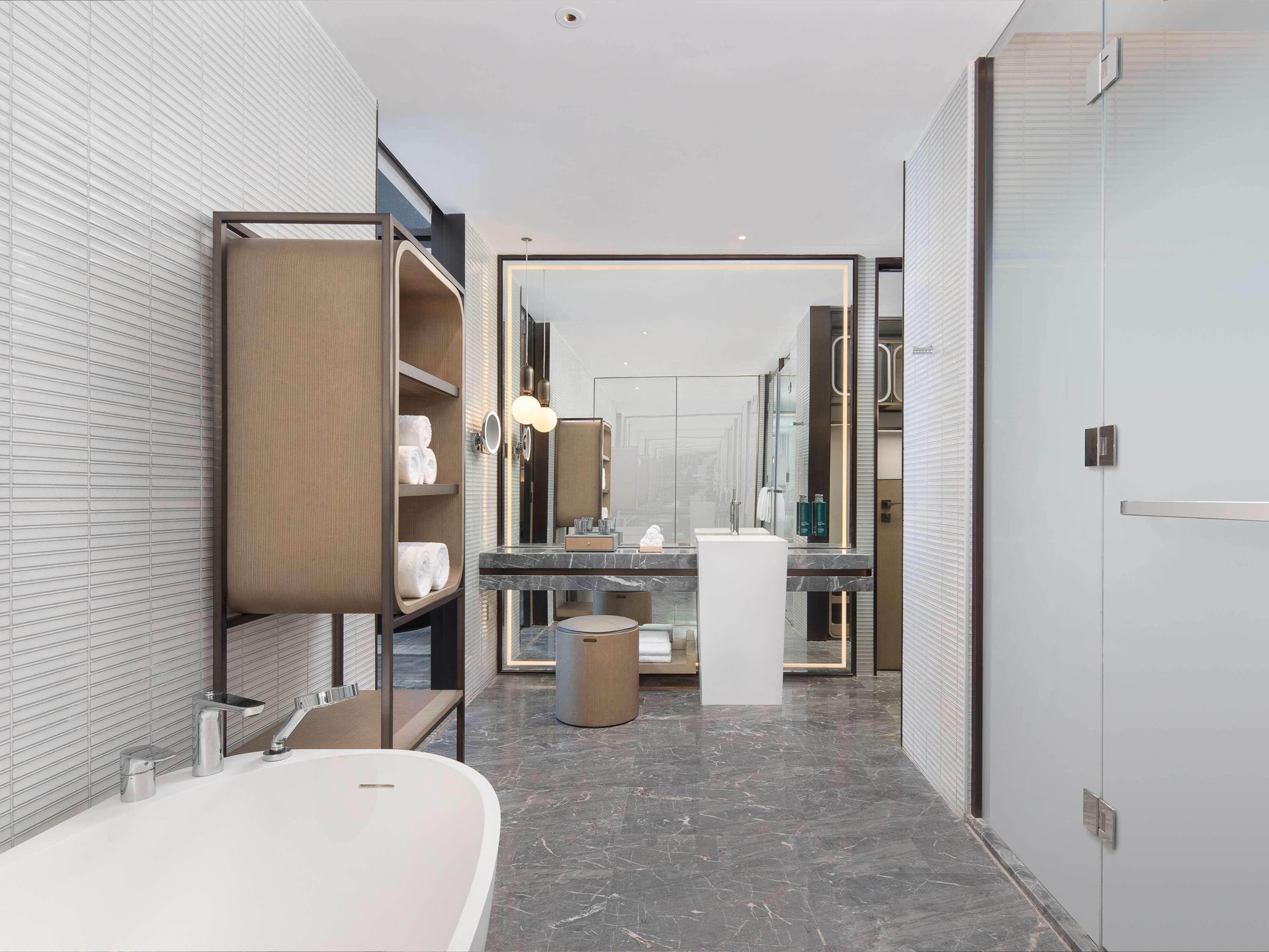 Un baño moderno con una bañera independiente, un tocador con un espejo grande y un perchero para toallas.