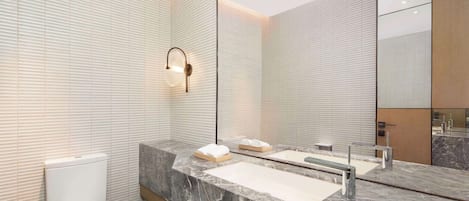 A modern bathroom with a marble vanity, a toilet, and a large mirror.