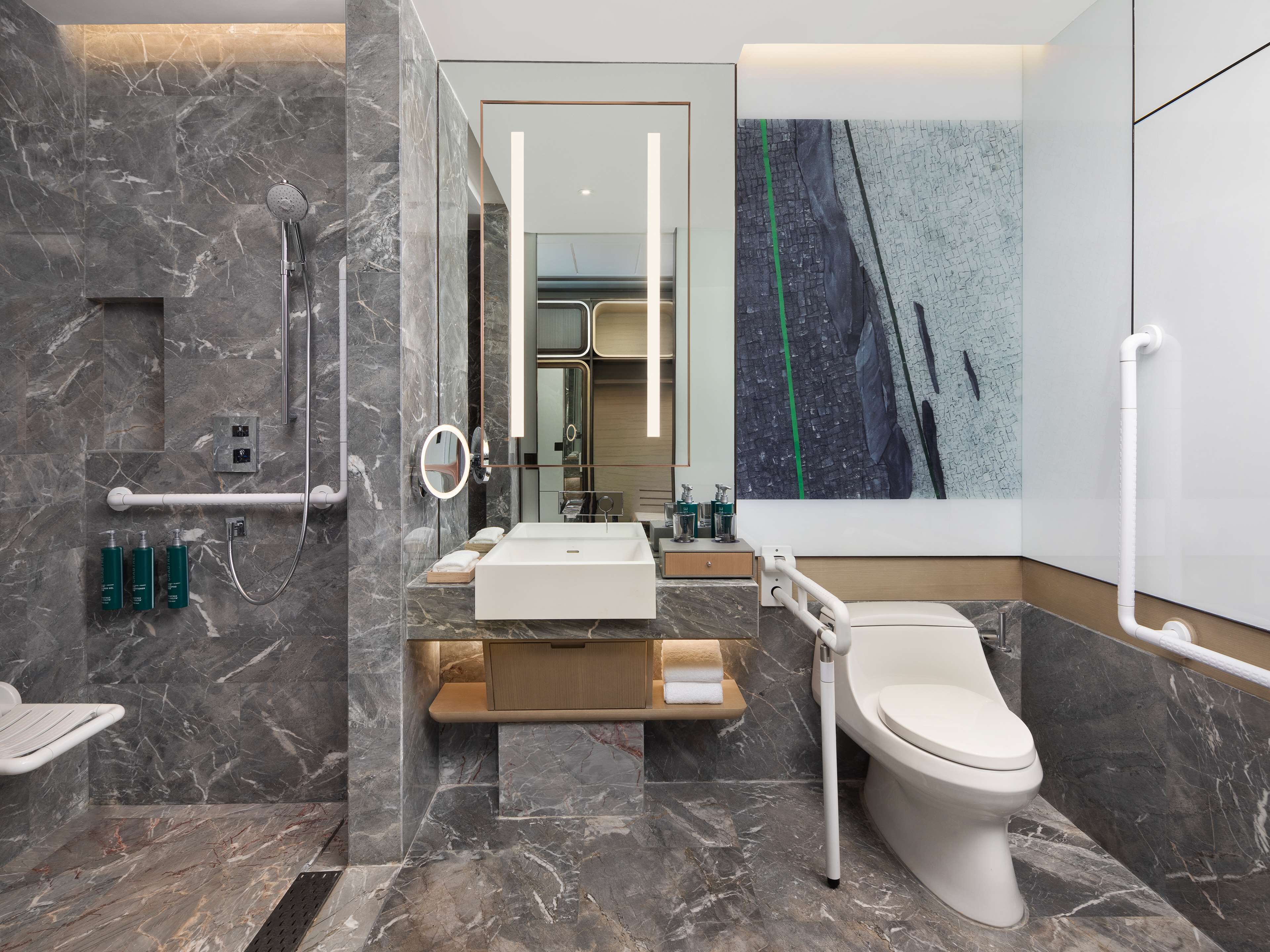 Un baño moderno con suelo de mármol, lavamanos blanco, inodoro y zona de ducha.