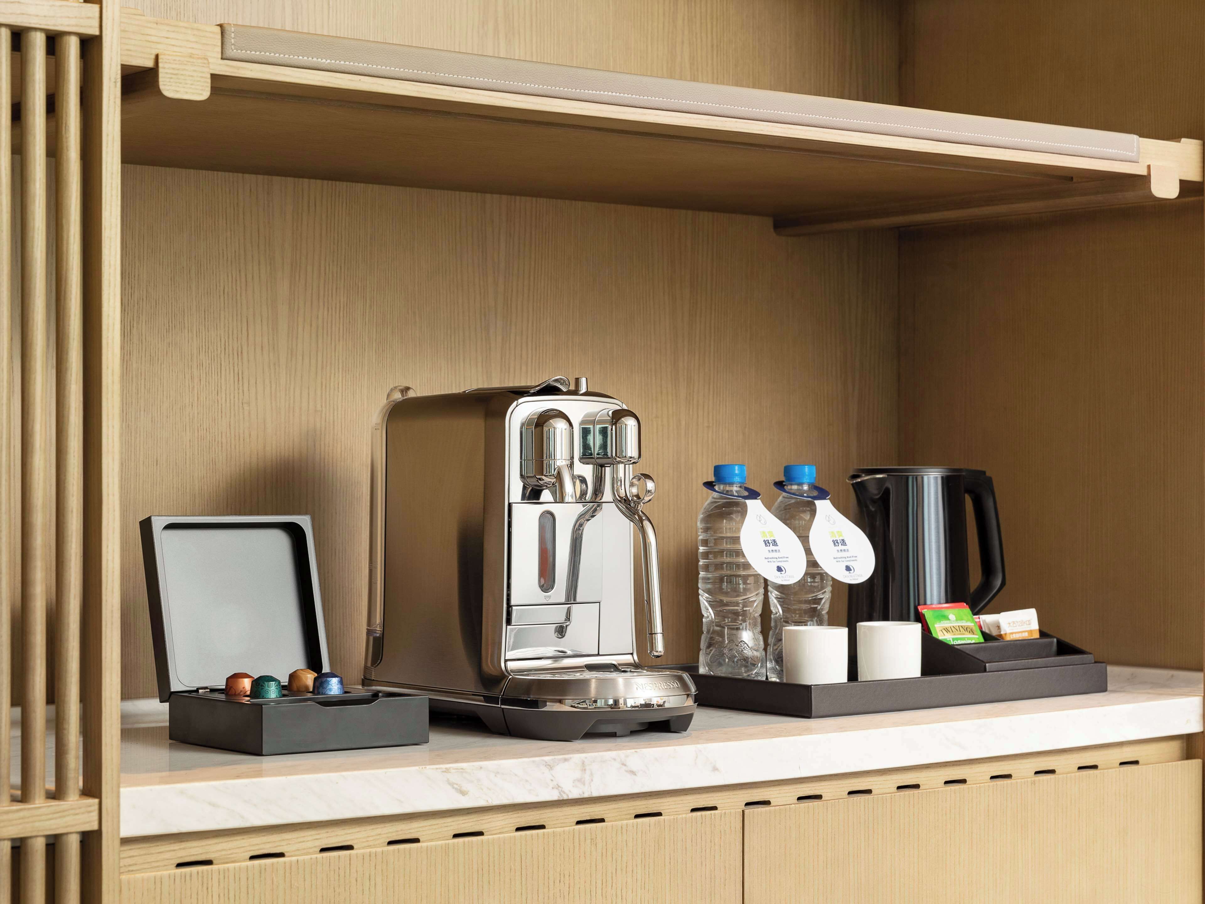 A kitchenette with a coffee maker, water bottles, and a coffee pot.