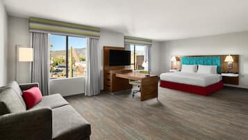 Een hotelkamer met een bed, een bureau, een televisie en uitzicht op de woestijn.
