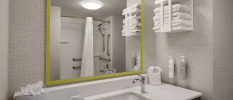 A modern bathroom with a large mirror, a sink, and a towel rack.