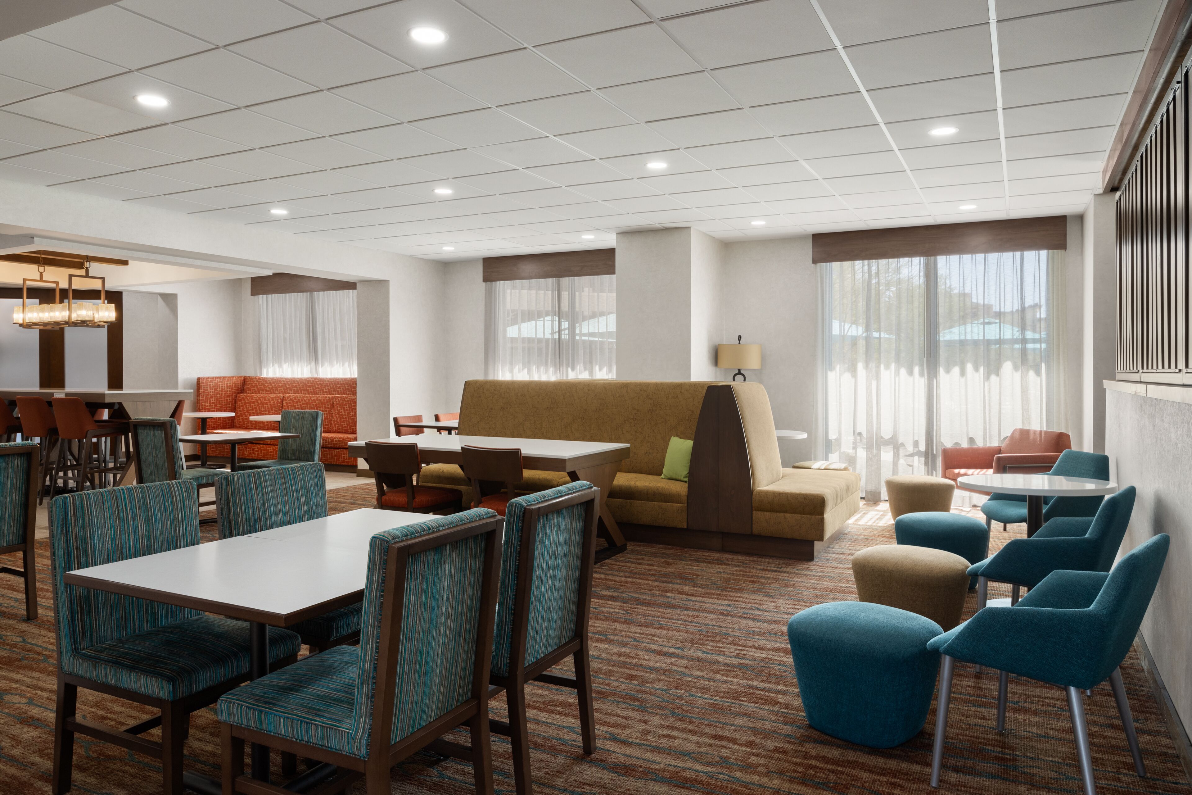 Un hall d’hôtel comprenant un espace repas, des canapés et un sol recouvert de moquette.