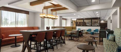 A modern hotel lobby with a bar area, seating arrangements, and a reception desk.