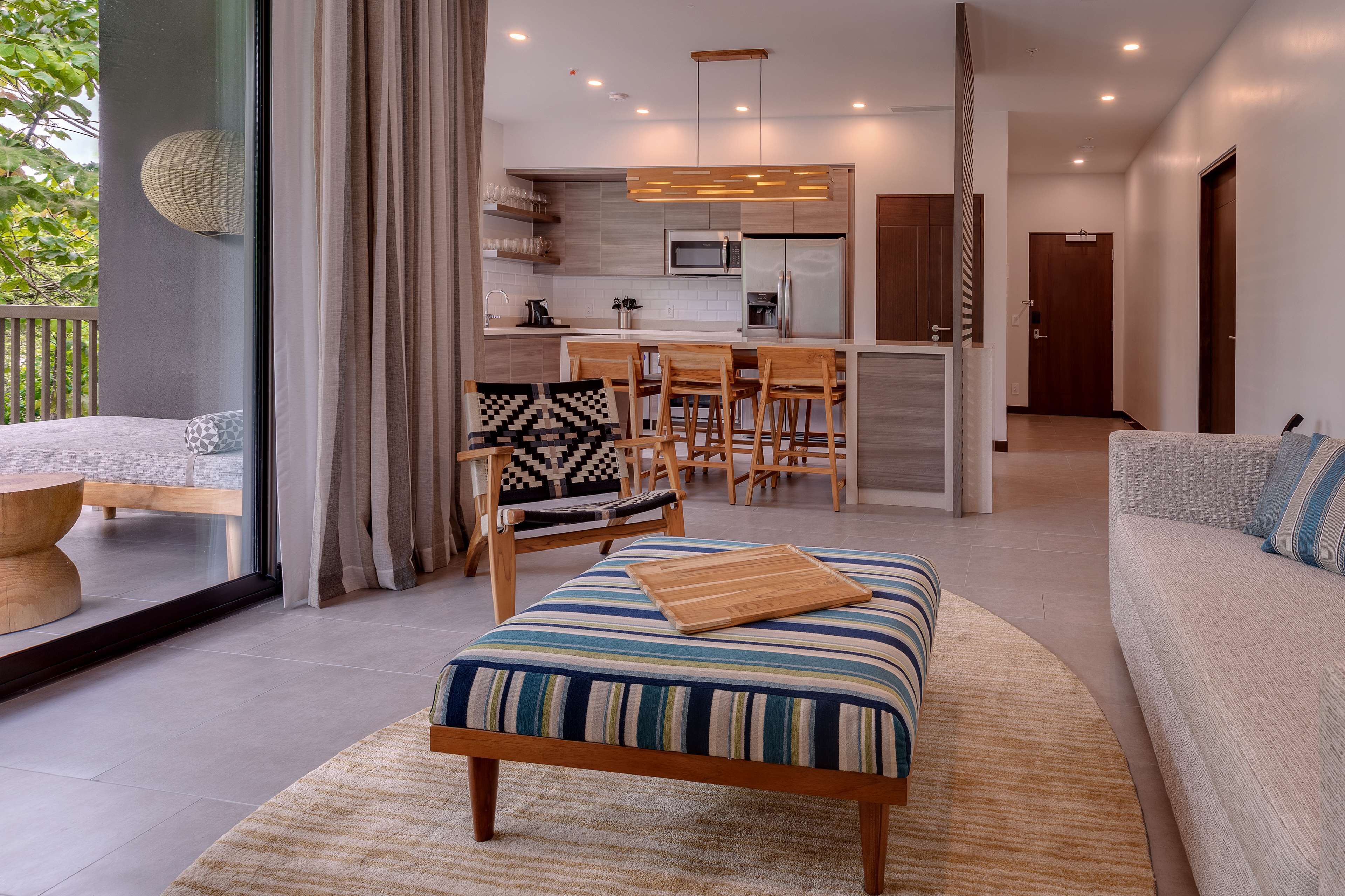 A modern living room with a sofa, ottoman, and dining area.