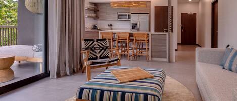 A modern living room with a sofa, ottoman, and dining area.