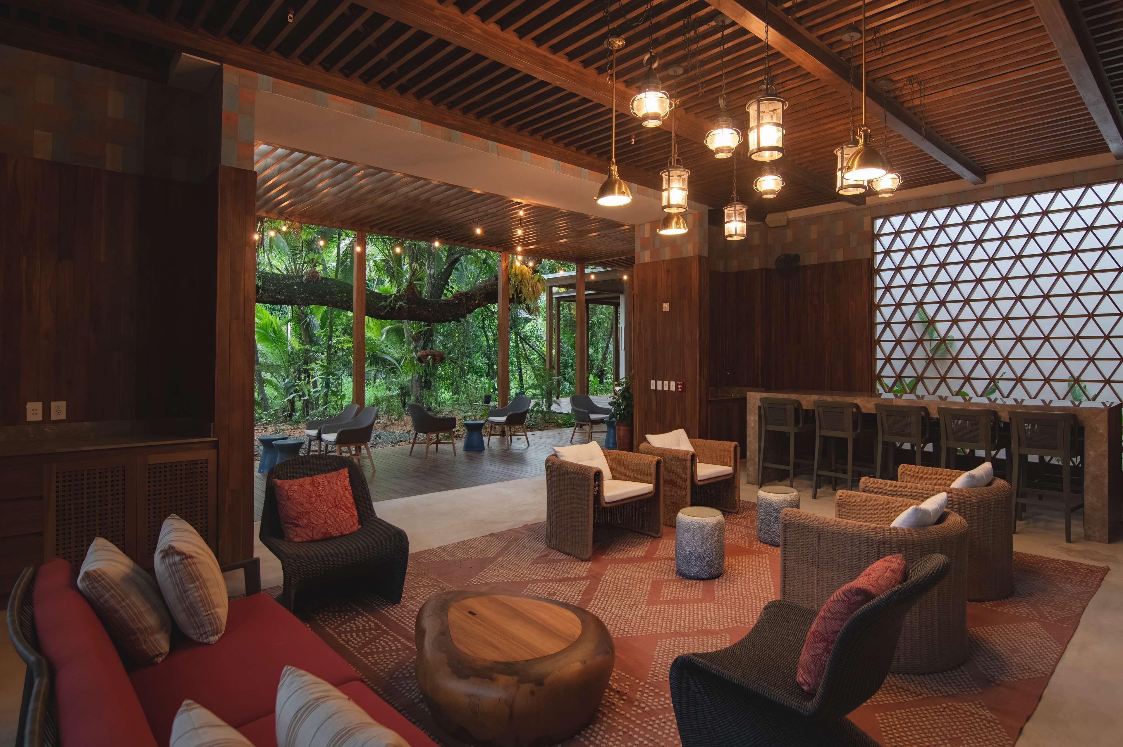 Un espace intérieur vaste et lumineux, agrémenté de meubles en osier, d’éléments décoratifs en bois et de luminaires suspendus.