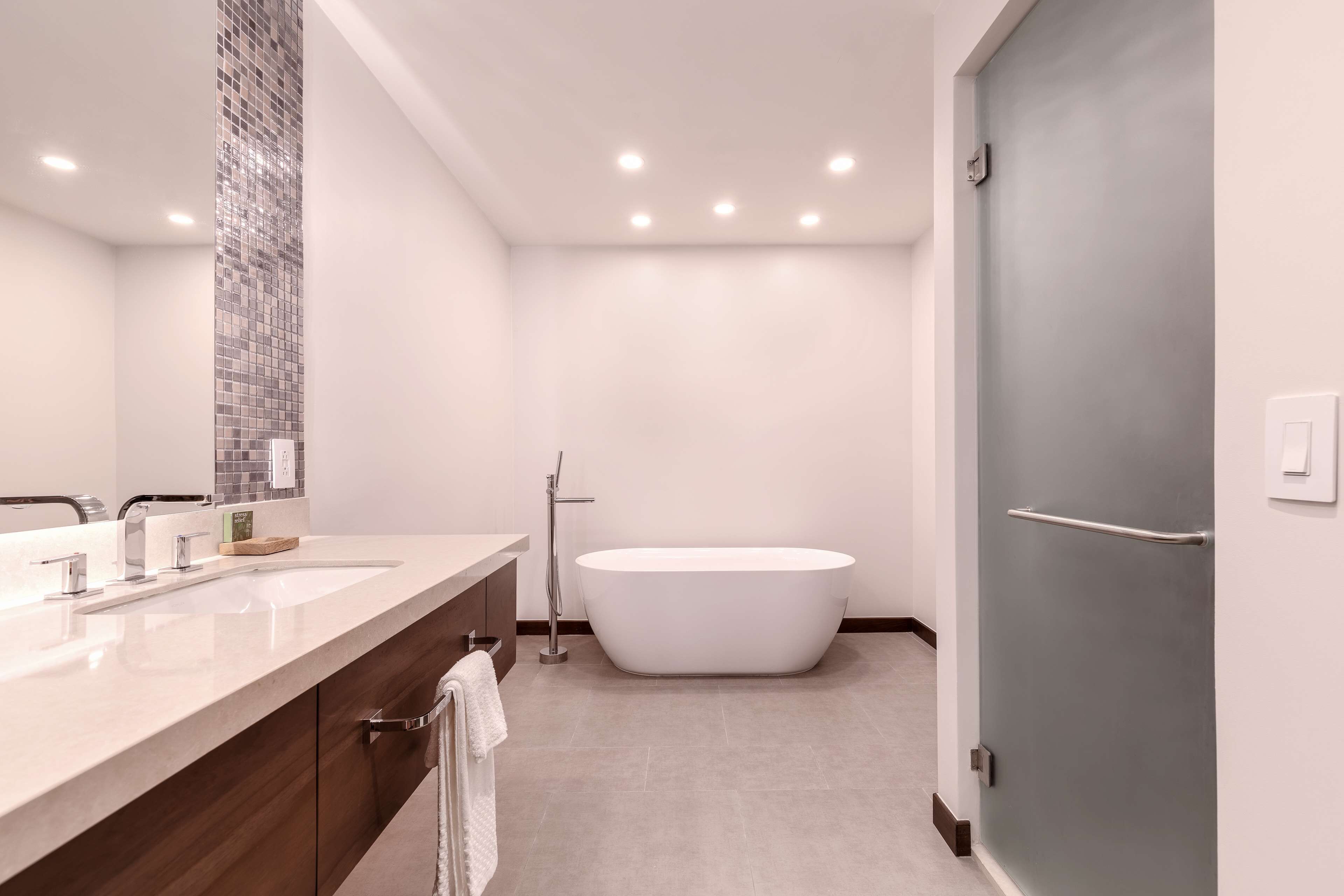 Une salle de bain moderne avec une baignoire sur pieds, un grand miroir et un meuble-lavabo doté d’un évier et d’un porte-serviettes.