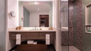 Un baño moderno con un espejo grande, dos lavamanos, un tocador y una zona de ducha.