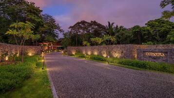 A gravel road leading to a building with a stone wall and a sign that reads "BOTANIKA."