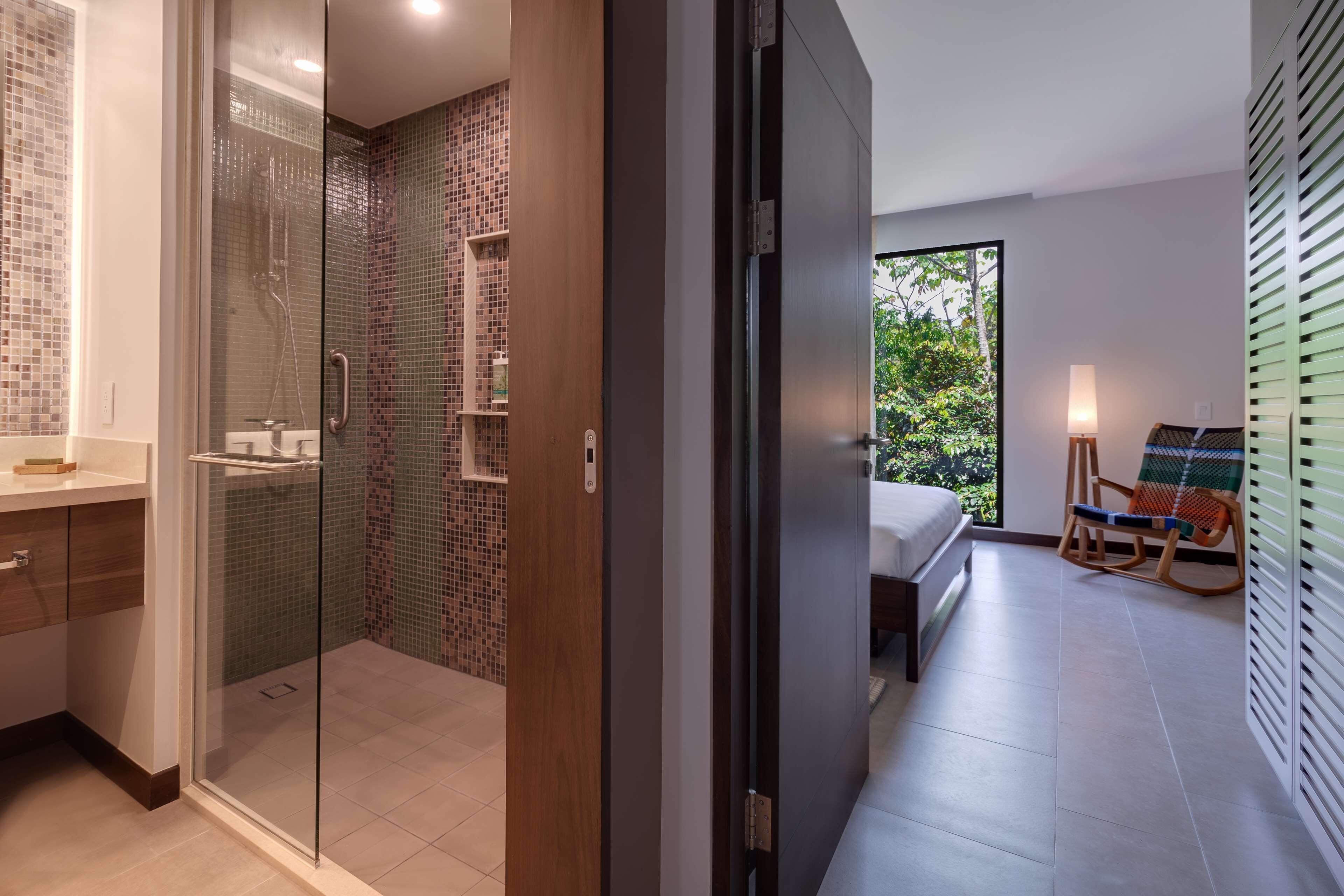 Een moderne badkamer met een douchecabine van glas, een houten wastafelmeubel en een betegelde douche.