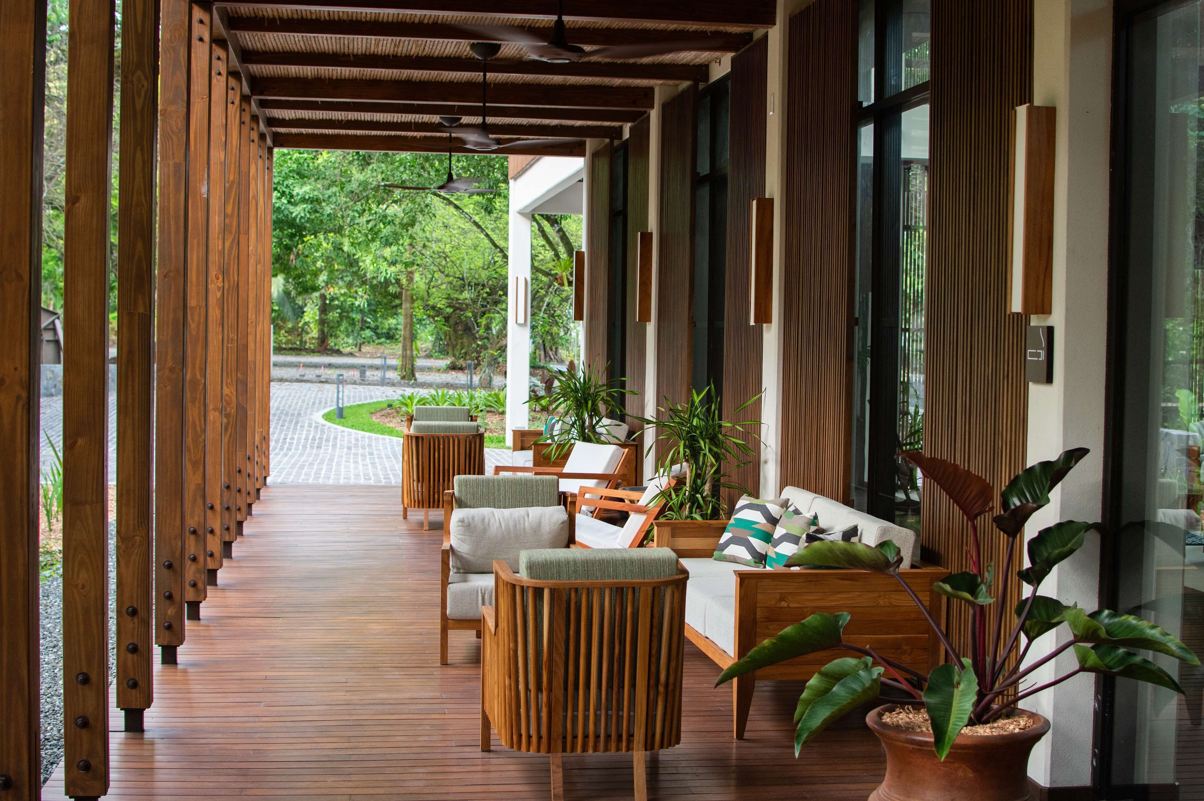 A covered outdoor seating area with wooden furniture and potted plants.