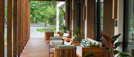 A covered outdoor seating area with wooden furniture and potted plants.